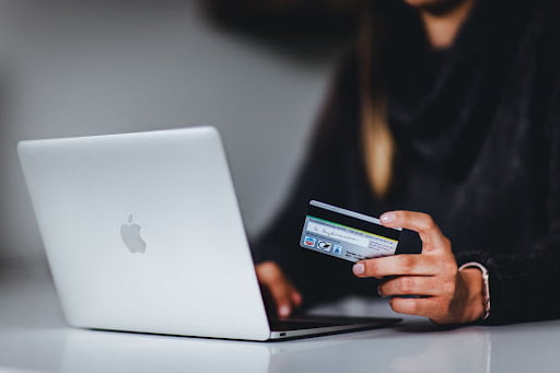woman using her laptop and holding a credit card to do some online shopping