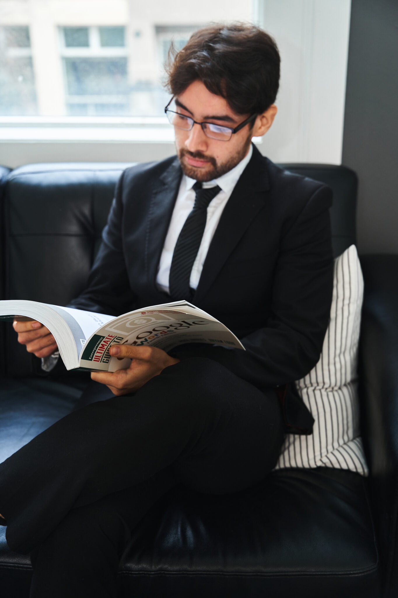 man sitting on couch reading a book