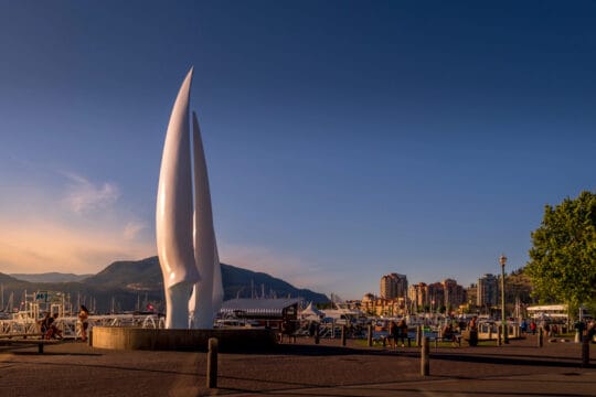 Scenic view of Kelowna, British Columbia, Canada, featuring Okanagan Lake, surrounding mountains, and a vibrant cityscape under clear skies, representing a popular destination for tourism and local business growth.