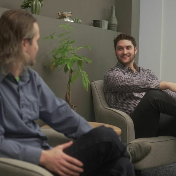two people sitting on couches discussing work